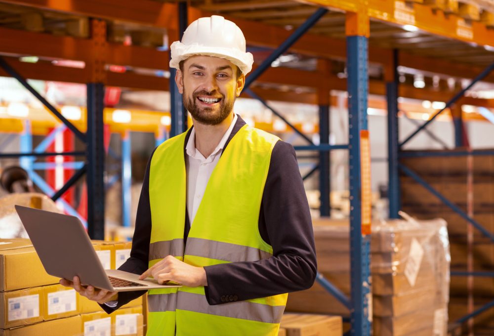 Logistics system. Happy cheerful man looking at you while organizing the logistics system of the warehouse